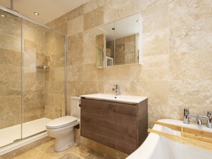 A modern bathroom with a glass-enclosed shower, a white toilet, a wooden vanity with a sink, and a mirror above the vanity. - Walton House Cottage (High Peak)