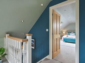 A staircase with white balusters leading to a bedroom with a bed and a nightstand. - Walton House Cottage (High Peak)