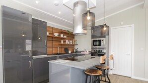 A modern kitchen with a central island, stainless steel appliances, wooden cabinets, and pendant lighting.