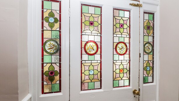 A white door with four stained glass panels, each featuring a bird and floral design.