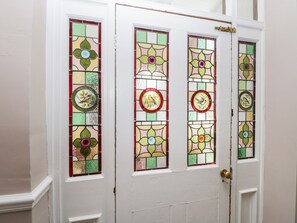 Una puerta blanca con cuatro paneles de vidrio emplomado, cada uno con un diseño de aves y flores.