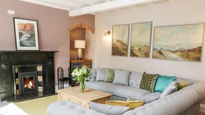 A living room with a fireplace, a sofa, a coffee table, and artwork on the wall.