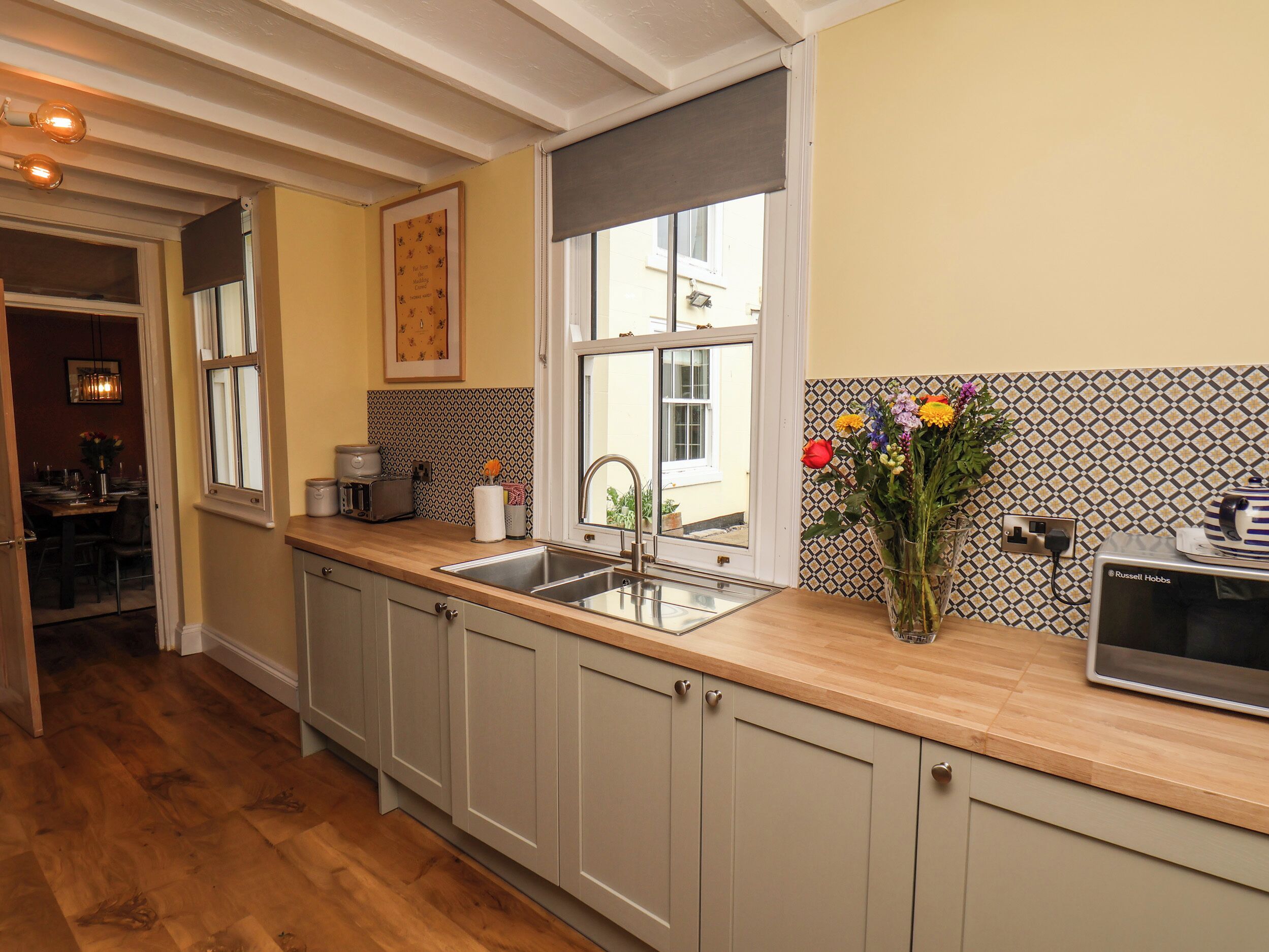 A kitchen with wooden cabinets, a sink, a toaster, and a vase with flowers.