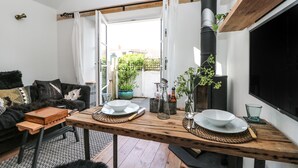 Una sala de estar acogedora con una mesa de madera lista para comer, un sofá negro y una pantalla de televisión grande.