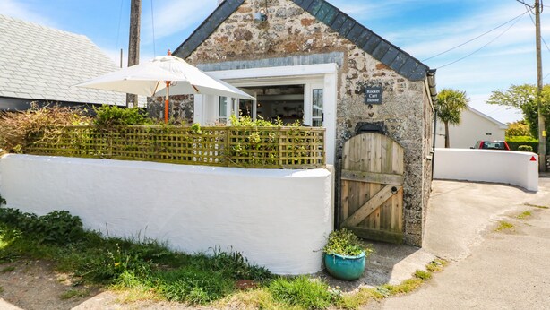 Un edificio rústico con fachada de piedra, puerta de madera y pared exterior blanca.