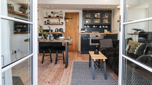 Una cocina moderna con pisos de madera, un comedor con una silla de cuero negro y un tapete de diseño blanco y negro.