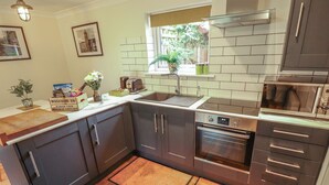 A modern kitchen with dark cabinets, a built-in oven, a microwave, and a window with a view of greenery.