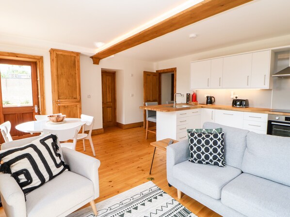 A compact living space with a dining area, a kitchenette, and a sofa with patterned cushions.