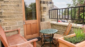 Eine Holztür, ein runder Tisch mit Stühlen und ein Blumentopf auf einem Balkon.