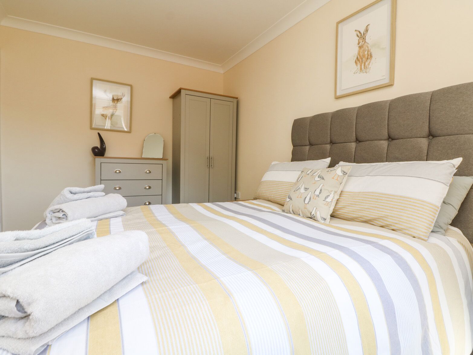 A bedroom with a bed, a wardrobe, a dresser, and a framed picture on the wall.
