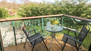 Ein Balkon mit zwei Stühlen, einem Tisch, einer Weinflasche und einem Glas Wasser.