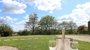 A table with a metal bucket and two glasses on a white tablecloth outdoors. - Hillcrest (Retford)
