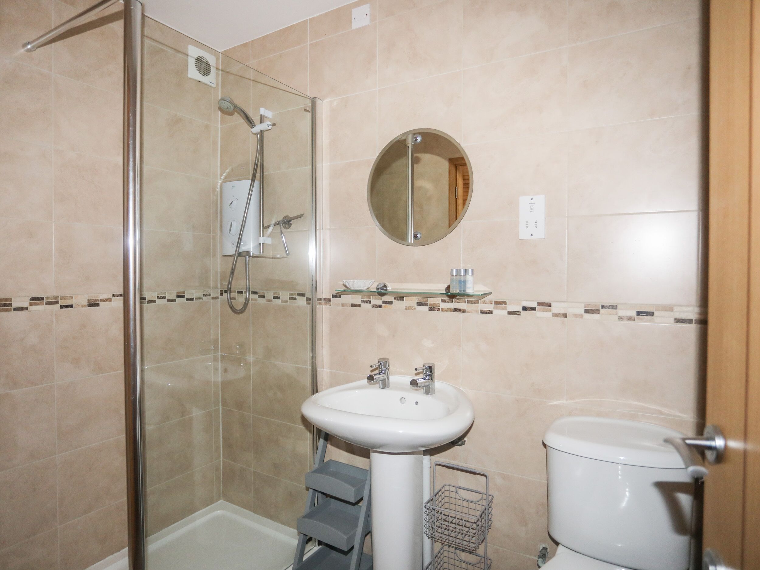 A bathroom with a glass-enclosed shower, a white sink, and a toilet.