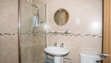 A bathroom with a glass-enclosed shower, a white sink, and a toilet.