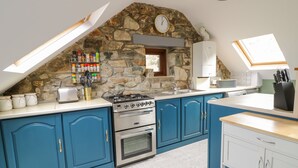 Una cucina con mobili blu, una parete in pietra, un fornello a gas e un lucernario.