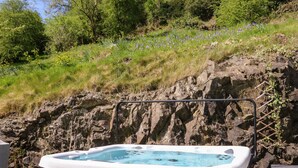 Ein Whirlpool in naturer Umgebung mit einer felsigen Hügelsicht und viel Grün im Hintergrund.