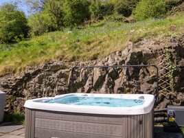 Un jacuzzi en un entorno natural, con un risco rocoso y vegetación al fondo.