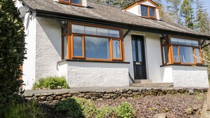 Ein zweistöckiges Haus mit Steinaußenwand, großen Fenstern und einem Steinfundament.