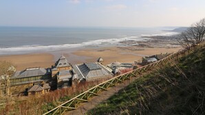 A coastal building complex with multiple domed structures, a wooden walkway, and a beach in the background. - Seafarers (Scarborough)
