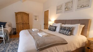 A neatly made bed with a beige blanket and pillows, a wooden wardrobe, and a framed picture on the wall. - Seafarers (Scarborough)