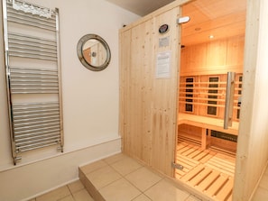 A sauna room with wooden walls, a metal door, and a tiled floor. - Seafarers (Scarborough)