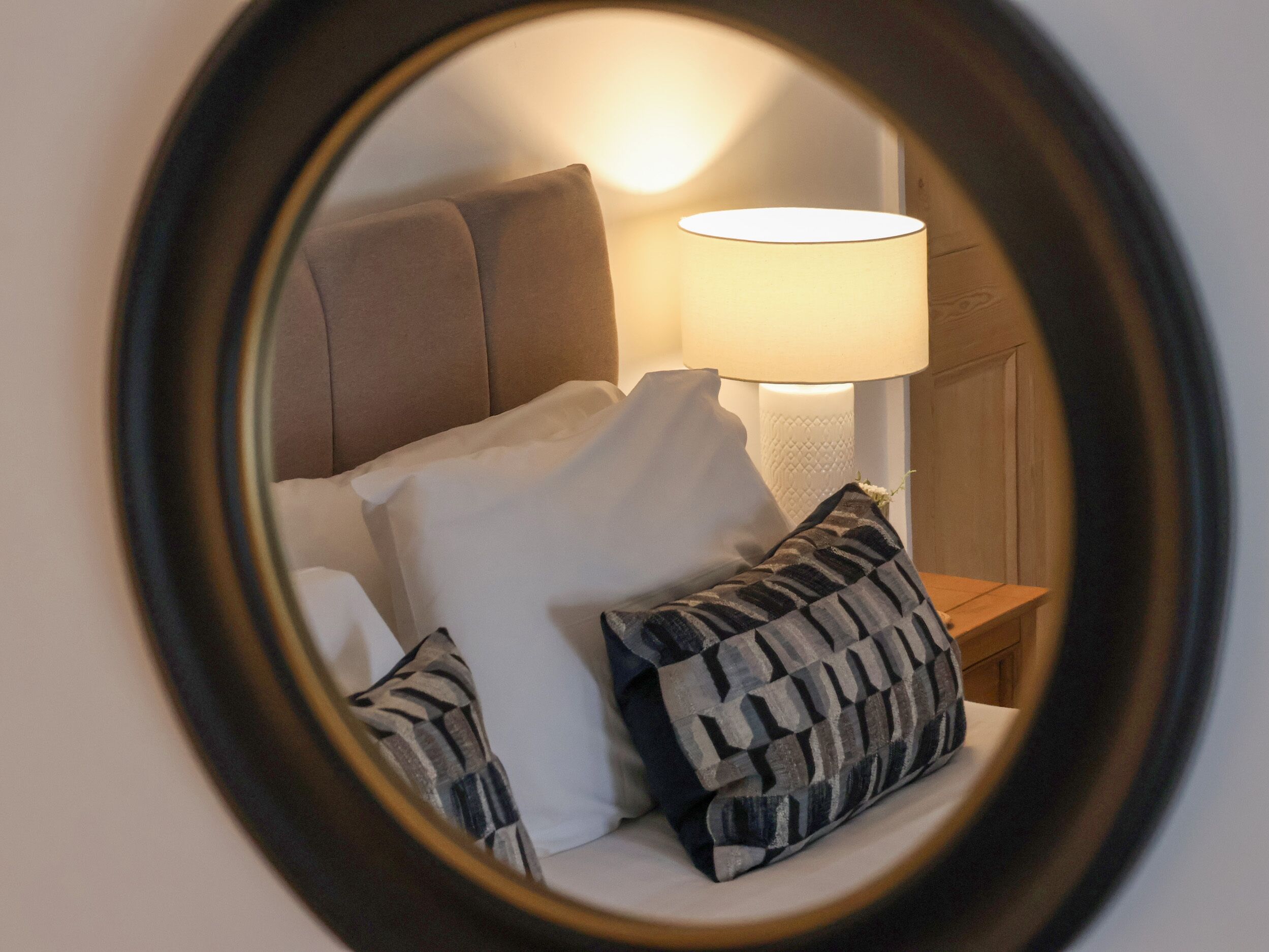 Un letto con cuscini e una lampada in una stanza.
