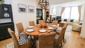 A dining area with a round table set for six, surrounded by wicker chairs with patterned cushions. - Seafarers (Scarborough)