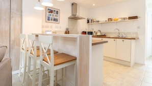 Een moderne keuken met witte kasten, een houten keukeneiland, hanglampen en een postkantoorbord.
