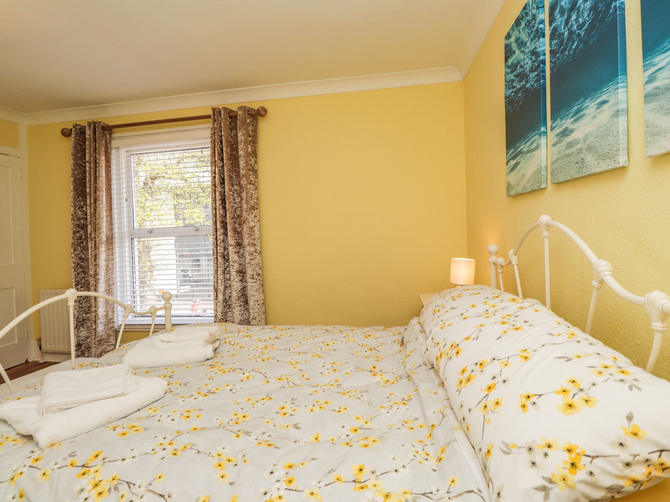 Un dormitorio con cama, cortinas, una ventana y un cuadro en la pared.