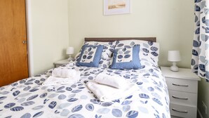A neatly made bed with a leaf-patterned duvet, two pillows, and two bedside lamps. - 20 Siesta Mar (Norwich)