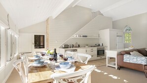 A spacious dining area with a wooden table set for a meal, a kitchen with modern appliances, and a cozy seating area with a brown sofa. - Protestant Hall - complete peace and tranquility (Wildes Meadow)