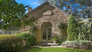 A stone building with a plaque reading 'Protestant Hall 1874,' a large arched doorway, and a well-maintained garden with various plants. - Protestant Hall - complete peace and tranquility (Wildes Meadow)