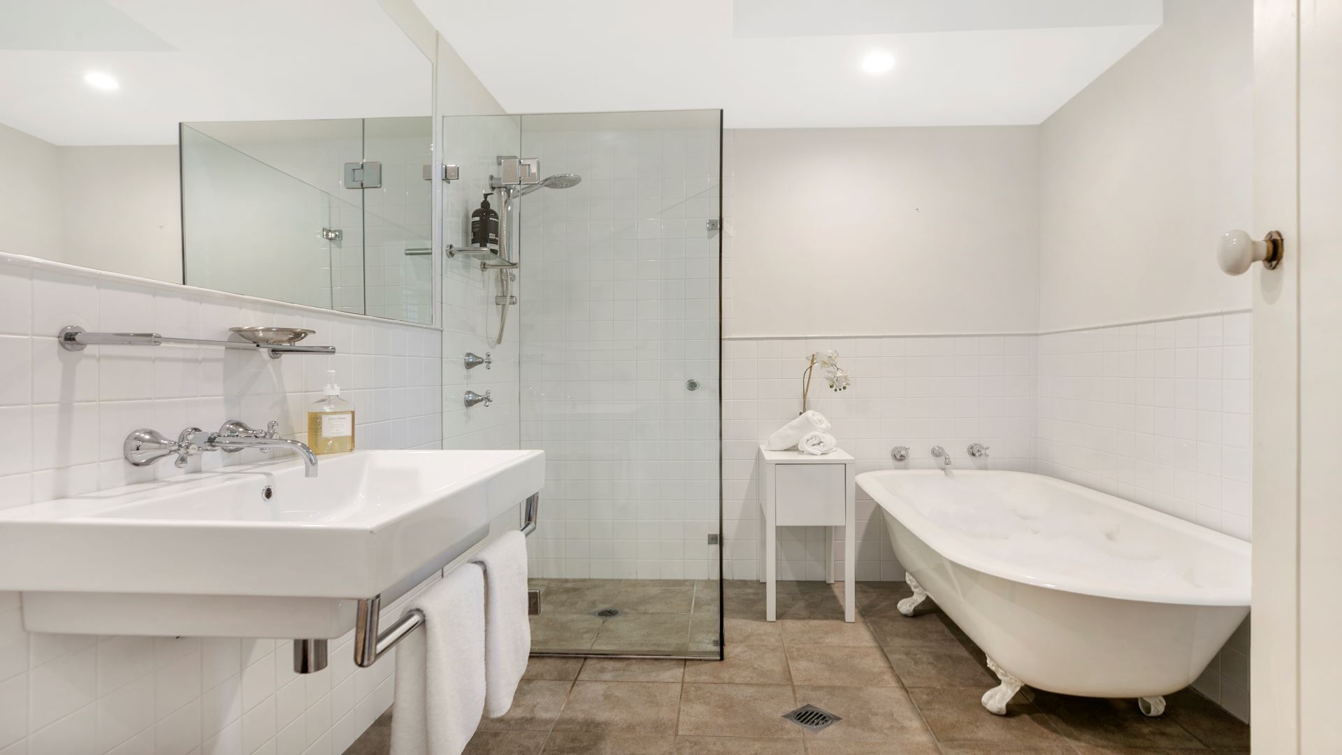 Ein modernes Badezimmer mit einer einteiligen Duschkabine, einer freistehenden Badewanne und einem Waschtisch mit Spiegel.