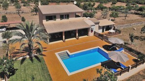 A two-story house with a swimming pool, surrounded by palm trees and a dry landscape. - Ballester 034 fantastic finca with private pool, large terrace, barbecue and air conditioning (Santa Margalida)
