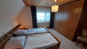 Et soveværelse med en træseng, et natbord, en stol og et klædeskab.