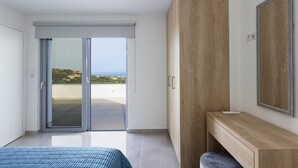 Et moderne soveværelse med en skydedør til en balkon, en trækommode og et stort spejl.