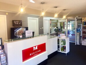 A reception area with a glass counter, a Red Star Hotels sign, and a display of bottled water.
