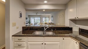 Una cocina con armarios blancos, encimeras de granito y un lavabo doble.