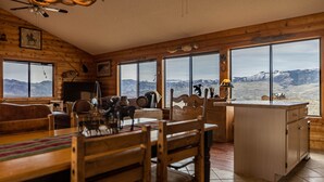 Una cabaña acogedora con paredes de madera y ventanas amplias que ofrecen vistas a la montaña.