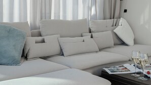 A modern living room with a sectional sofa, a blue throw pillow, and a magazine on a coffee table. - Arcimboldo House 2+2, Emma Villas (Sirmione)