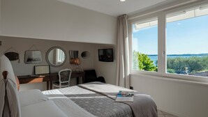 A bedroom with a bed, a desk, a chair, and a large window with a view of the outdoors. - Arcimboldo House 2+2, Emma Villas (Sirmione)