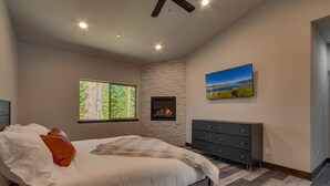 A bedroom with a bed, a fireplace, a dresser, and a large window. - Built in 2021, Chef's Kitchen, Classic Arcade, 200mbps Wifi, Grill, Close to Heavenly: North Woods (South Lake Tahoe)