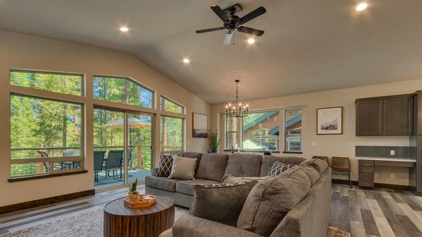 A spacious living room with a large sectional sofa, a coffee table, and a view of a deck with outdoor furniture. - Built in 2021, Chef's Kitchen, Classic Arcade, 200mbps Wifi, Grill, Close to Heavenly: North Woods (South Lake Tahoe)