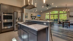 A modern kitchen with built-in appliances, a large island, and a dining area with a view. - Built in 2021, Chef's Kitchen, Classic Arcade, 200mbps Wifi, Grill, Close to Heavenly: North Woods (South Lake Tahoe)