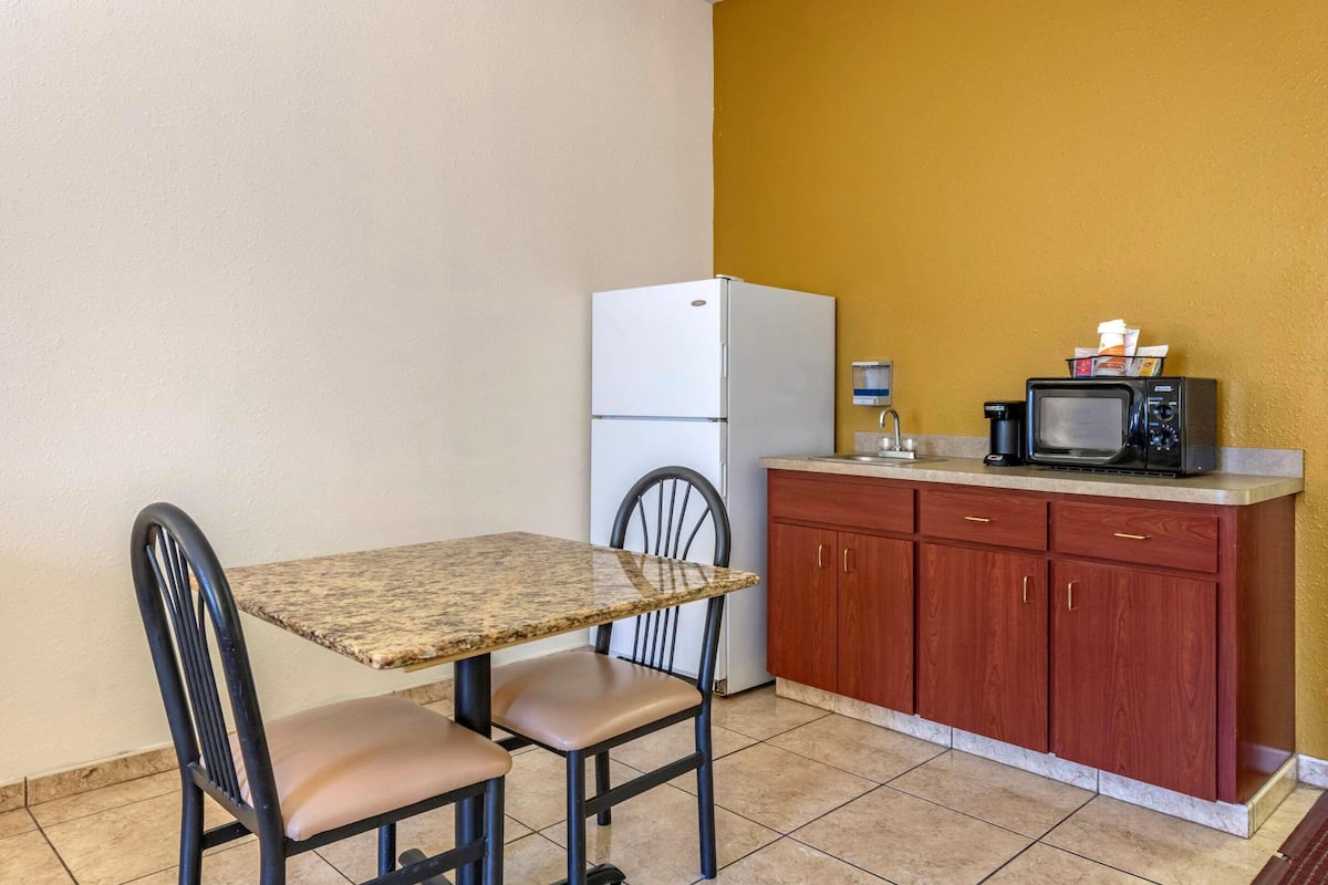 Una cocina compacta con encimera de granito, un refrigerador blanco, un microondas y armarios de madera.