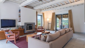 A modern living room with a flat-screen TV, a fireplace, a sofa, and a balcony with curtains. - Villa Le Fontane 12, Emma Villas (Todi)