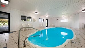 An indoor swimming pool with a tiled floor, a metal pool ladder, and white walls. - Ramada by Wyndham Effingham (Effingham)