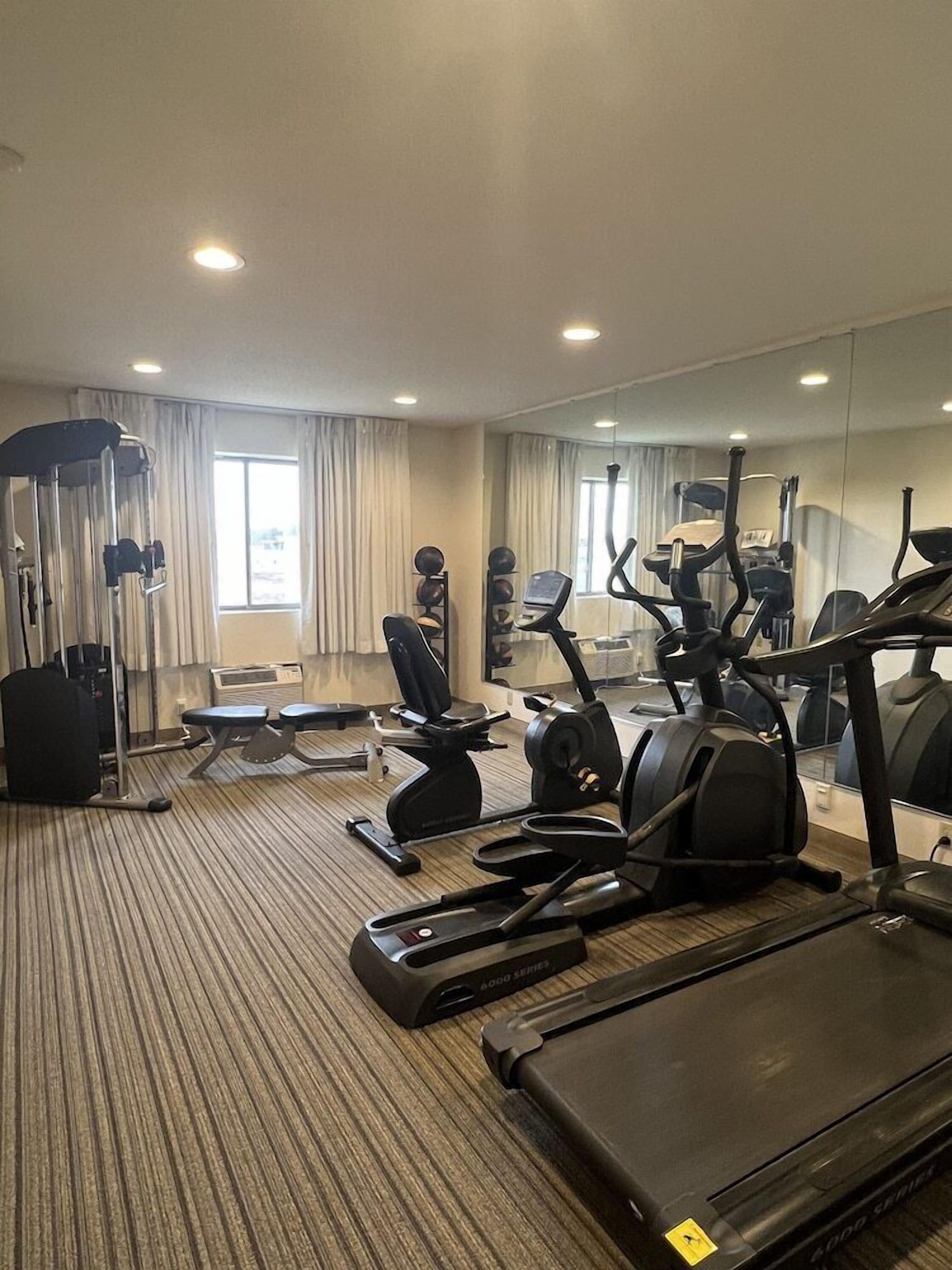A hotel gym with cardio equipment, weight machines, and a mirrored wall.