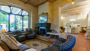 A cozy living room with a fireplace, comfortable seating, and a view of the outdoors. - La Casa Di Nanì 8, Emma Villas (San Lorenzo In Noceto)