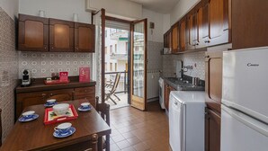 A compact kitchen with wooden cabinets, a white refrigerator, and a dining table set with blue and white dishes.